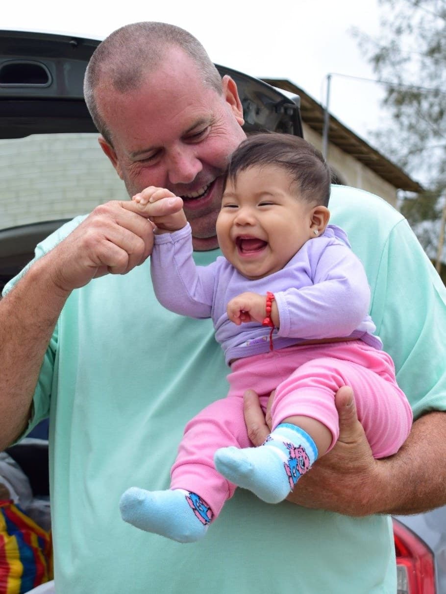 A man from the OpenSoul Foundation holding a laughing child